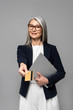 © LIGHTFIELD STUDIOS - smiling asian businesswoman with grey hair shopping online with credit card and laptop isolated on grey
