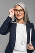 © LIGHTFIELD STUDIOS - smiling asian businesswoman with grey hair holding laptop isolated on grey