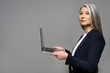 © LIGHTFIELD STUDIOS - attractive serious asian businesswoman with grey hair using laptop isolated on grey