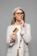 © LIGHTFIELD STUDIOS - thoughtful asian businesswoman with grey hair holding credit card isolated on grey