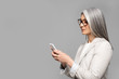 © LIGHTFIELD STUDIOS - beautiful asian businesswoman in eyeglasses with grey hair talking on smartphone isolated on grey