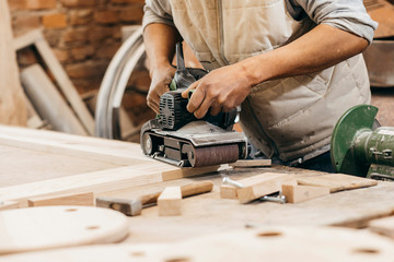 Worker grinds the wood of angular grinding machine