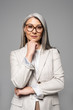 © LIGHTFIELD STUDIOS - pensive asian businesswoman in eyeglasses isolated on grey