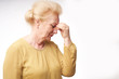 © Roman Ribaliov - An elderly woman holds her hands on her sore head on a white background