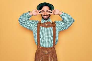 Wall Mural - Young handsome man wearing tratidional german octoberfest custome for Germany festival Doing peace symbol with fingers over face, smiling cheerful showing victory