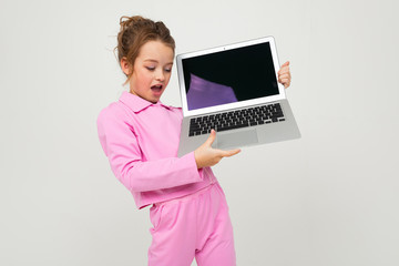 Closeup portrait of an attractive young girl in a pink suit showing a laptop screen with a mockup on a white background