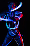 Fototapeta Psy - Portrait of a Girl with Glowing Tubes in Neon UF Light. Model Girl with Dreadlocks and Fluorescent Creative Psychedelic MakeUp, Art Design of Female Disco Dancer Model in UV, Colorful Abstract Make-Up