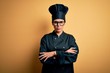 © Krakenimages.com - Young beautiful brunette chef woman wearing cooker uniform and hat over yellow background skeptic and nervous, disapproving expression on face with crossed arms. Negative person.