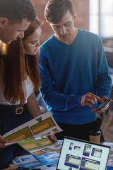 Colleagues sharing mobile phone discussing web design