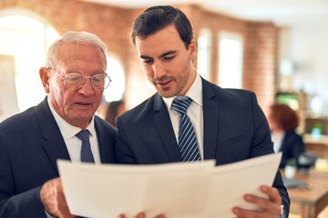 Two business workers working together. Speaking and reading documents standing at the office