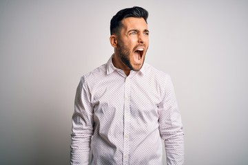 Canvas Print - Young handsome man wearing elegant shirt standing over isolated white background angry and mad screaming frustrated and furious, shouting with anger. Rage and aggressive concept.