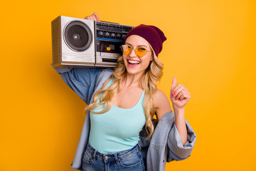 Sticker - Photo of attractive lady long hairdo good mood free time hold shoulder vintage tape recorder wear casual turquoise singlet denim shirt sun specs headwear isolated yellow color background