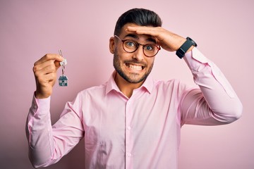 Sticker - Young real estate business man holding new house keys over pink background stressed with hand on head, shocked with shame and surprise face, angry and frustrated. Fear and upset for mistake.