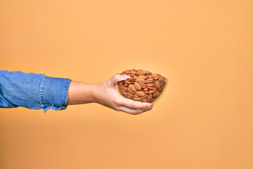 Wall Mural - Beautiful hand of woman holding bowl with baked german pretzels over isolated yellow background