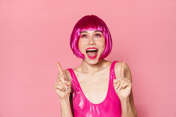 Wall Mural - Image of excited girl expressing surprise and pointing fingers upward