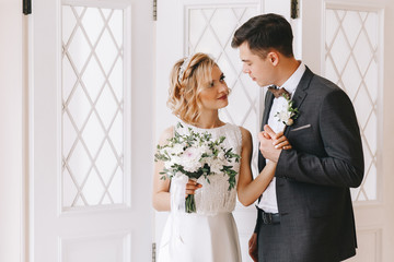 Bride and groom. Portrait of a man in a suit and a blonde woman in a white vintage dress in a classic interior on a wedding day.