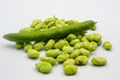  open green broad beans in their shells and some shelled beans isolated on a white background