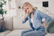 © deagreez - Profile photo of unwell displeased blond lady sitting couch stay home quarantine hold hand forehead suffer pms have headache touch back massaging injured pain place living room indoors
