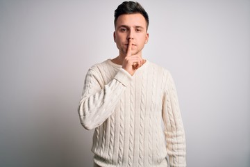 Young handsome caucasian man wearing casual winter sweater over white isolated background asking to be quiet with finger on lips. Silence and secret concept.