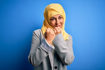 Sticker - Middle age brunette business woman wearing muslim traditional hijab over blue background Ready to fight with fist defense gesture, angry and upset face, afraid of problem