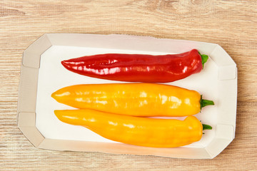 Wall Mural - three pods of sweet pepper lie in a cardboard tray on the table