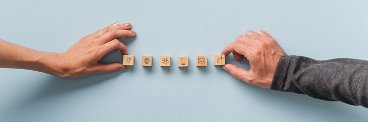 Fototapete - Male and female hands placing wooden blocks with contact and communication icons on  them in a row