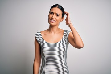 young beautiful brunette woman wearing casual striped dress over isolated white background confuse a