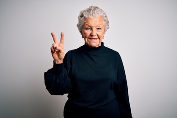 Wall Mural - Senior beautiful woman wearing casual black sweater standing over isolated white background showing and pointing up with fingers number two while smiling confident and happy.