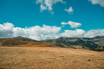 Beautiful view of a grass-covered field and mountains under the cloudy sky