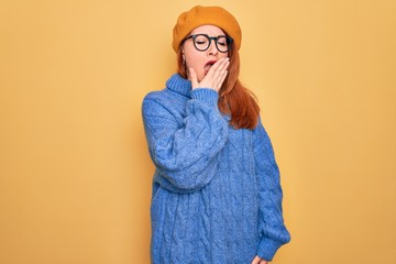 Wall Mural - Young beautiful redhead woman wearing french beret and glasses over yellow background bored yawning tired covering mouth with hand. Restless and sleepiness.