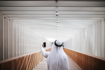 Wall Mural - Emirati guy taking selfie in the urban city lifestyle downtown the heart of Dubai.