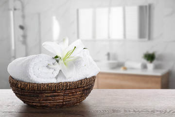 Wall Mural - Fresh towels and lily flower on wooden table in bathroom. Space for text