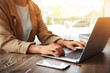© New Africa - Woman working with laptop at table in office, closeup