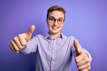 Young handsome redhead man wearing casual shirt and glasses over purple background approving doing positive gesture with hand, thumbs up smiling and happy for success. Winner gesture.