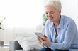 © Prostock-studio - Home leisure for seniors. Happy elderly woman using smartphone at home