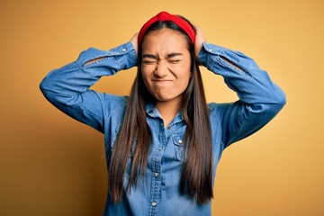 Sticker - Young beautiful asian woman wearing casual denim shirt and diadem over yellow background suffering from headache desperate and stressed because pain and migraine. Hands on head.