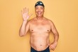 © Krakenimages.com - Middle age senior grey-haired swimmer man wearing swimsuit, cap and goggles showing and pointing up with fingers number five while smiling confident and happy.