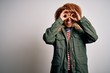 © Krakenimages.com - Young beautiful African American woman with curly hair wearing green casual winter coat doing ok gesture like binoculars sticking tongue out, eyes looking through fingers. Crazy expression.