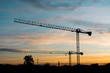 Silhouettes of tower cranes against the night sky House under construction. Industrial corner