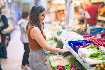 Wall Mural - Young beautiful woman smiling happy and confident. Standing with smile on face buying food at supermarket