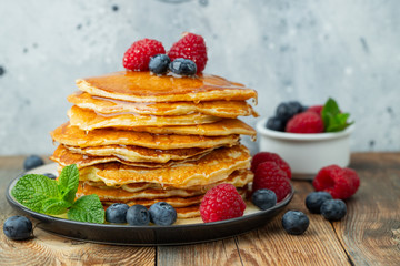 Close-up delicious pancakes, with fresh blueberries, raspberry's and honey on a light background