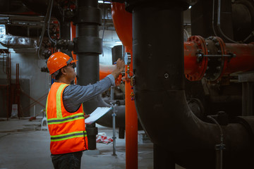 A engineer under checking the industry cooling tower air conditioner is water cooling tower air chiller HVAC of large industrial building to control air system.