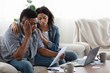 © Prostock-studio - Financial Crisis. Depressed black couple sitting with huge bills in living room