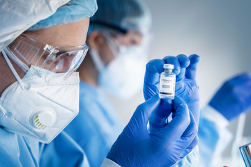 Wall Mural - coronavirus covid-19 vaccine bottle in hands of pharmacuetical and vaccine research scientist in lab