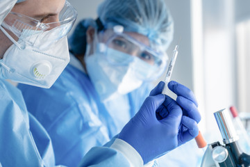 Wall Mural - coronavirus covid-19 vaccine injection syringe in hands of pharmacuetical and vaccine research scien