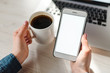 © Serhii - Woman's hands using blank screen cell phone, working, learns on laptop computer, drink coffee on table. Freelance. Work home. Online education. Communication, technology concept. Top view.