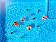 © artiemedvedev - Aerial of friends having party in swimming pool with inflatable flamingo, swan, mattress. Happy young people relax at luxury resort on sunny day. View from above. Girls in bikini sunbathing in a sun.