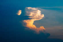 Large White Cumulus Clouds With Orange Sunset At Dusk And Blue Sky.