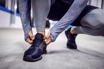 Closeup of man crouching and tying shoelace in underground garage.