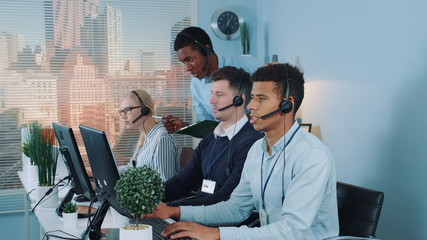 Wall Mural - Chief black manager of the call center giving recommendations to customer service representative, which making international call to the client.